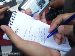 A person taking notes with a pen and a pad of paper