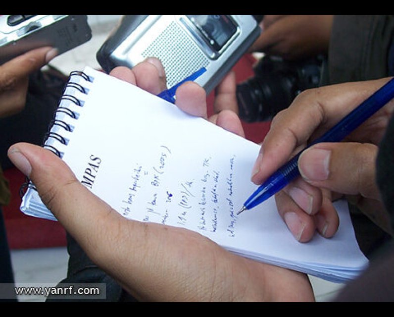 A person taking notes with a pen and a pad of paper