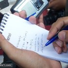 A person taking notes with a pen and a pad of paper